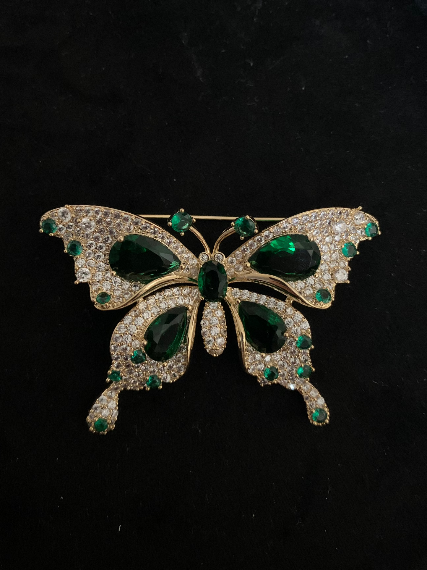 Elegant butterfly brooch with green gemstone, symbolizing beauty and transformation.