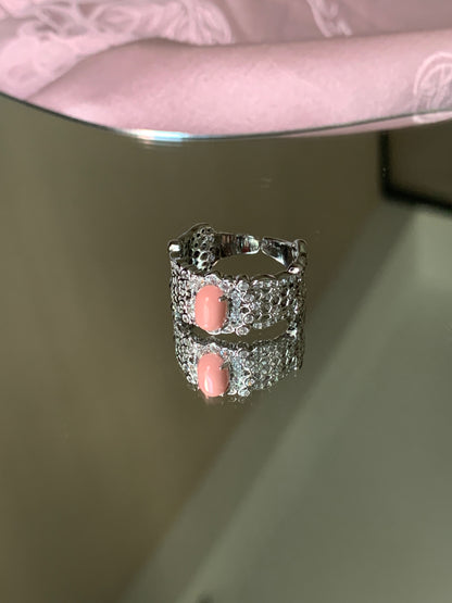 Harmony Power Rose Shell Ring elegantly displayed on a marble surface surrounded by soft flowers, creating a romantic atmosphere.