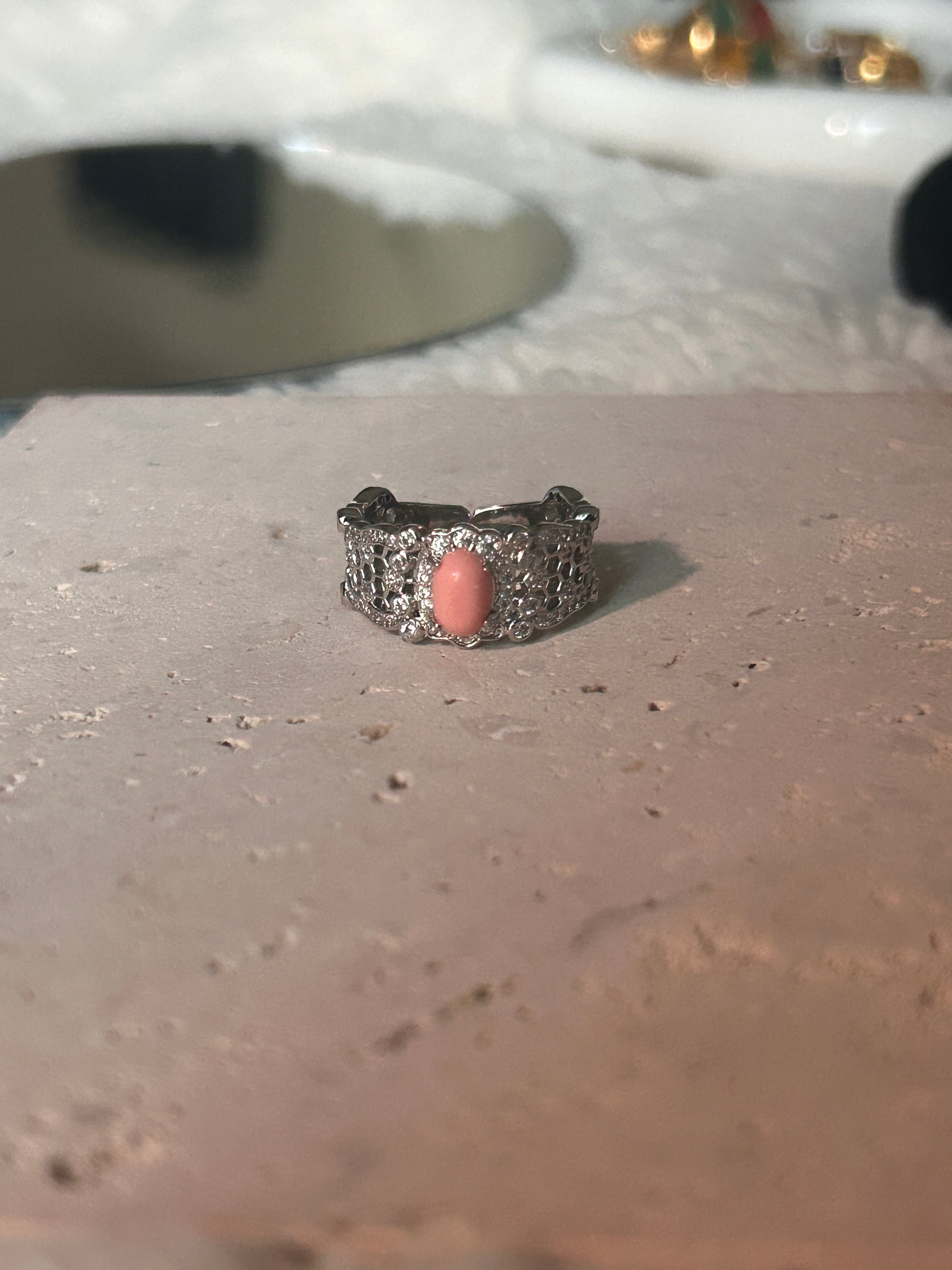 Harmony Power Rose Shell Ring captured among natural elements like seashells and soft greenery, reflecting its oceanic inspiration.