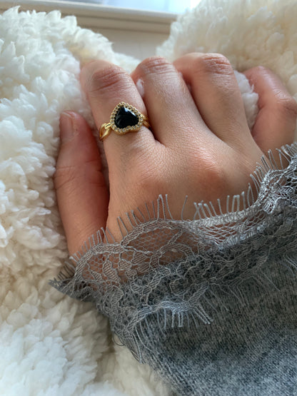 Lifestyle image of a woman showcasing her Love Power Obsidian Heart Gold Ring in a cozy setting, highlighting the ring's unique design and its symbol of love and strength.