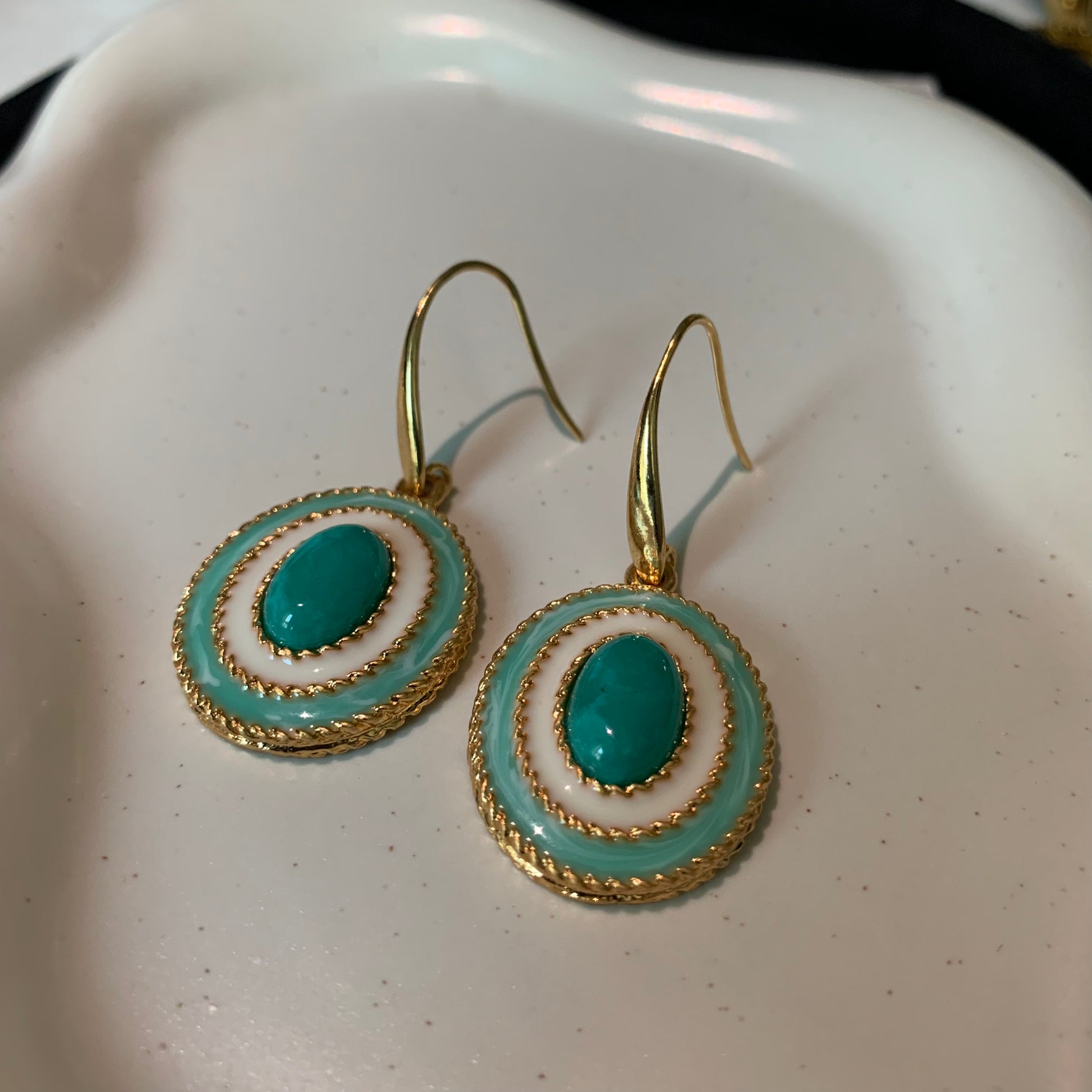Close-up of celestial design turquoise earrings with intricate metalwork